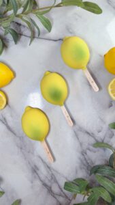 Premium Snow Lemon gelato sticks with crystalline coating artfully arranged on marble surface, showcasing Snowflake Gelato's latest Mediterranean dessert innovation