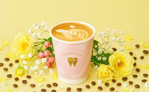Flat white coffee in Snowflake Gelato branded pink takeaway cup with latte art